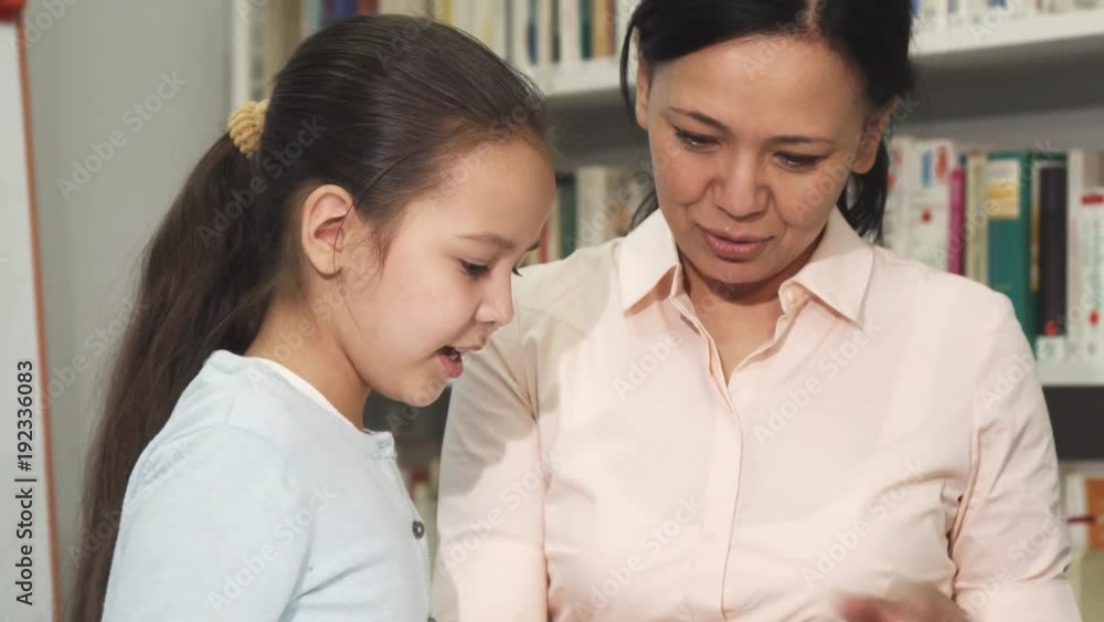 Mother and daughter choosing books at the library or bookstore Mother and daughter choosing books at the library or bookstore