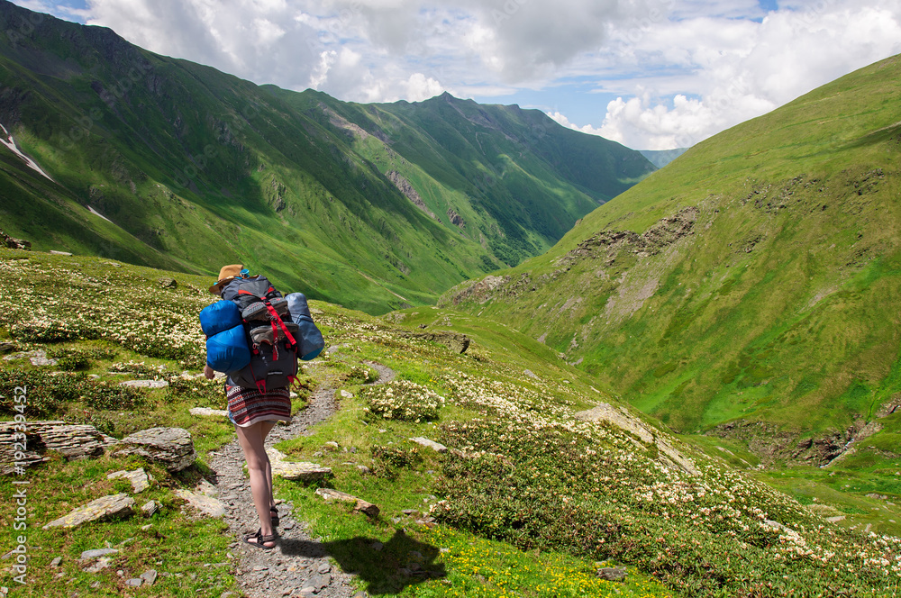Girl with a big backpack is traveling in the Caucasus mountains, Georgia.