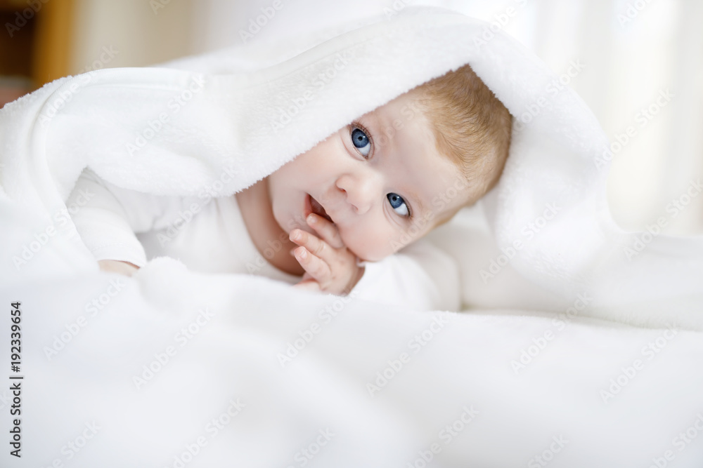 Baby girl wearing white towel or winter overal in white sunny bedroom Baby girl wearing white towel or winter overal in white sunny bedroom