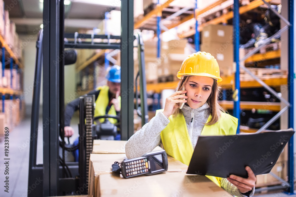 Warehouse workers with smartphone working together.