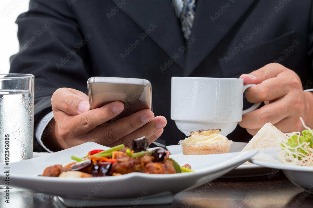Close up of Businessman checking the news from mobile phone while eatting breakfast on white background Close up of Businessman checking the news from mobile phone while eatting breakfast on white background