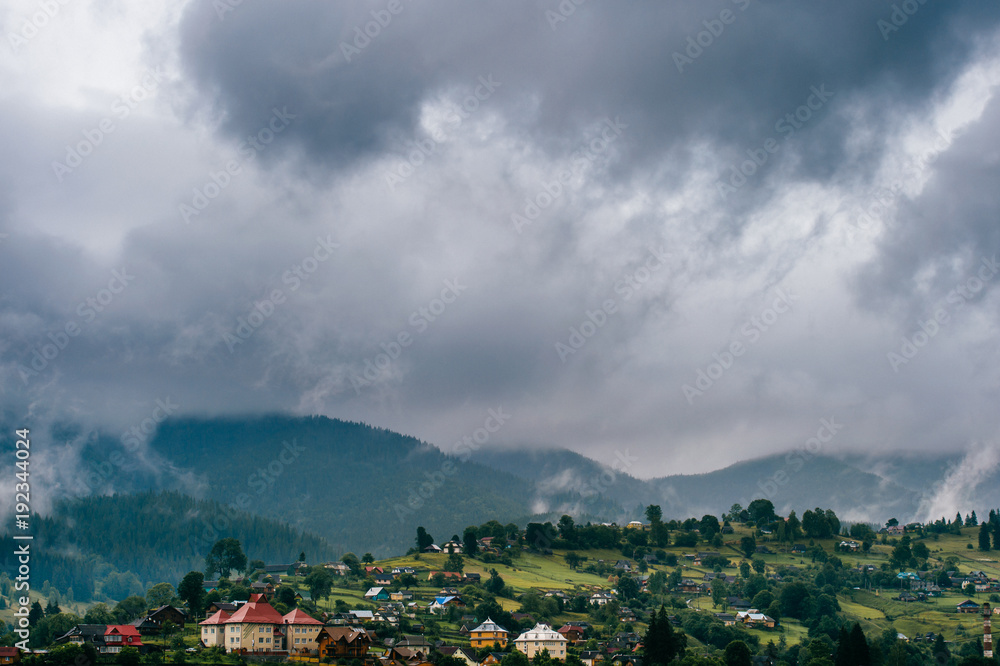 Beautiful nature landscape. Scenic view at misty foggy mountains peaks covered with rainy stormy clouds. Mystic hills with forest in summer. Discover Carpathians. Dramatic fable contryside wallpaper.