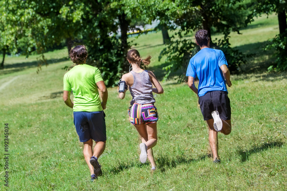 Fototapeta premium Woman and two young men running in the park
