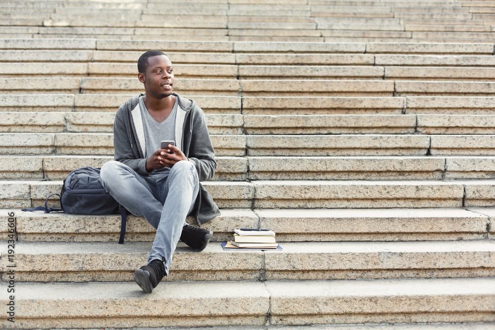 Happy african-american student using smartphone outdoors Happy african-american student using smartphone outdoors