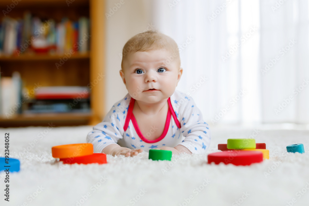 Cute baby girl playing with colorful wooden rattle toy Cute baby girl playing with colorful wooden rattle toy