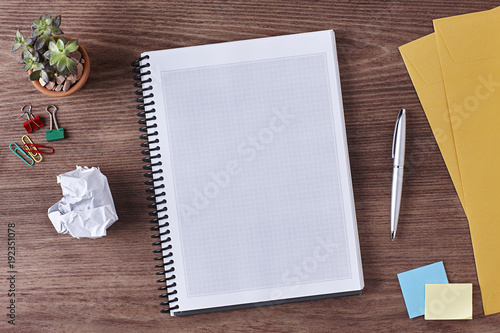 Office Workspace. Top View of a Business Workplace. Wooden Desk Table, Pen, Pencil, a Blank Notebook, Envelope, Plant Pot, Clips. Copy space for text or Image