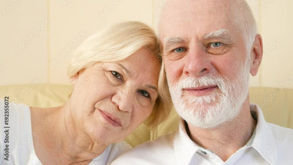Portrait of cheerful good-looking senior couple sitting on couch at home. Having good time relaxing together. Portrait of cheerful good-looking senior couple sitting on couch at home. Having good time relaxing together.