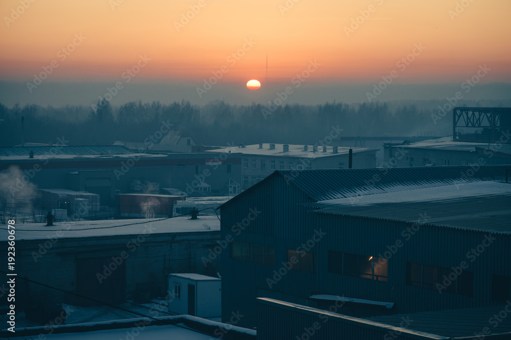 Industrial buildings in the sunrise. Sun in the center of the horizon. Industrial buildings in the sunrise. Sun in the center of the horizon.