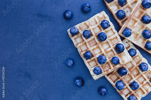 Waffles and blueberries breakfast on dark background with copy space