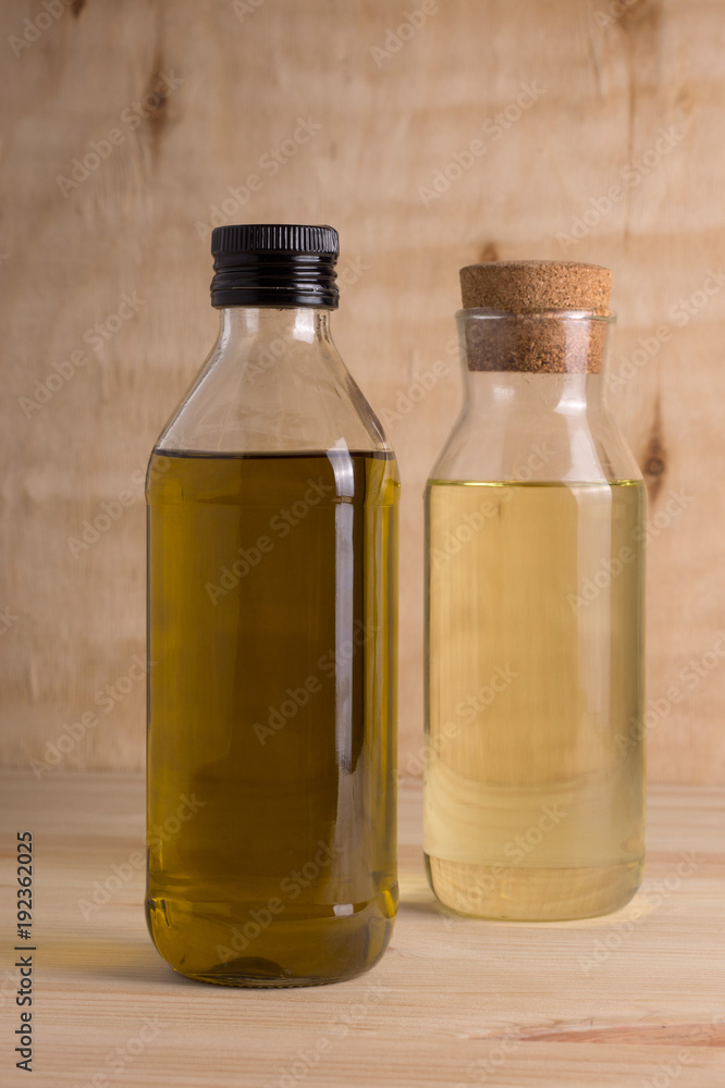 Olive and sunflower oil in glass bottle on wooden background Olive and sunflower oil in glass bottle on wooden background