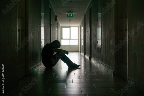 Silhouette of business man sitting alone., Sad and Serious Male sit and hug his knee alone of closeing office.With his reflect shadow. Dramatic moment. sad concept., hurt concept. lonely