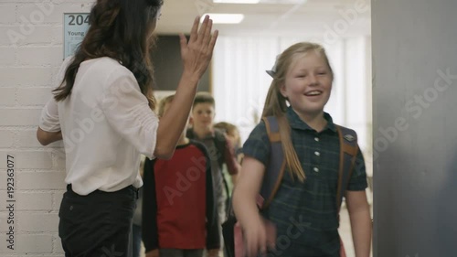 Enthusiastic teacher high-fiving students exiting doorway from classroom / Provo, Utah, United States