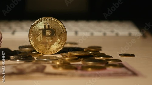 close up golden bitcoin coin and coins on keyboard and dollars banknotes background. selective focus photo