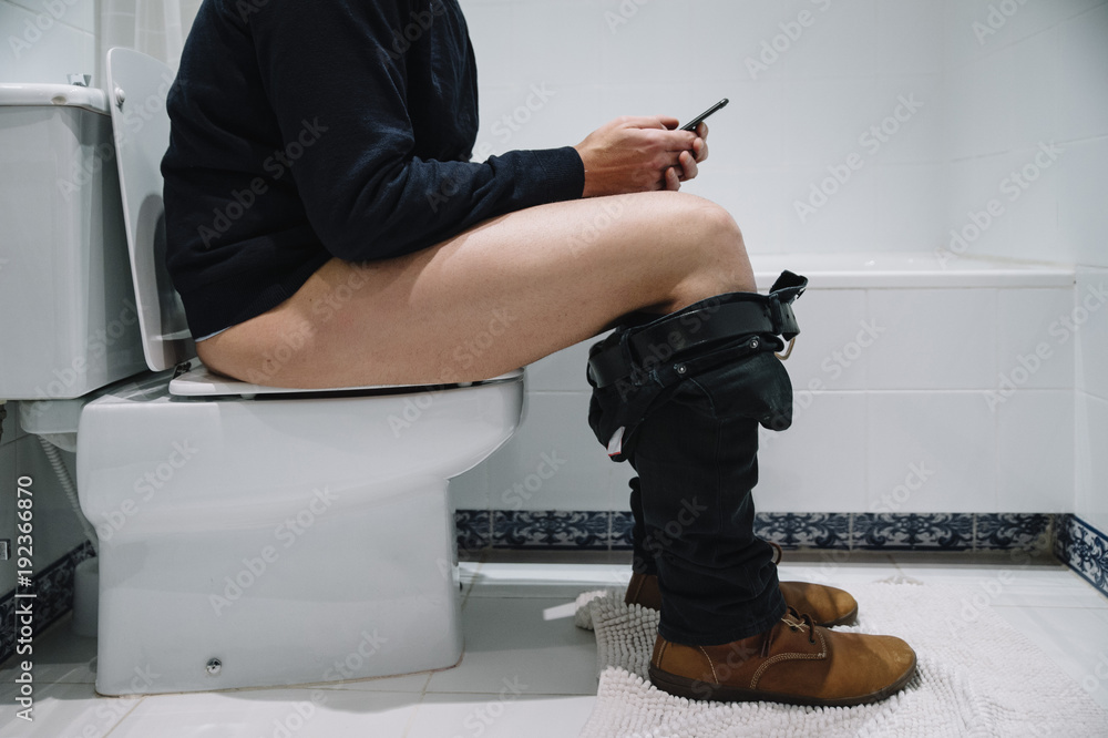 Fototapeta premium Man in the toilet with smartphone