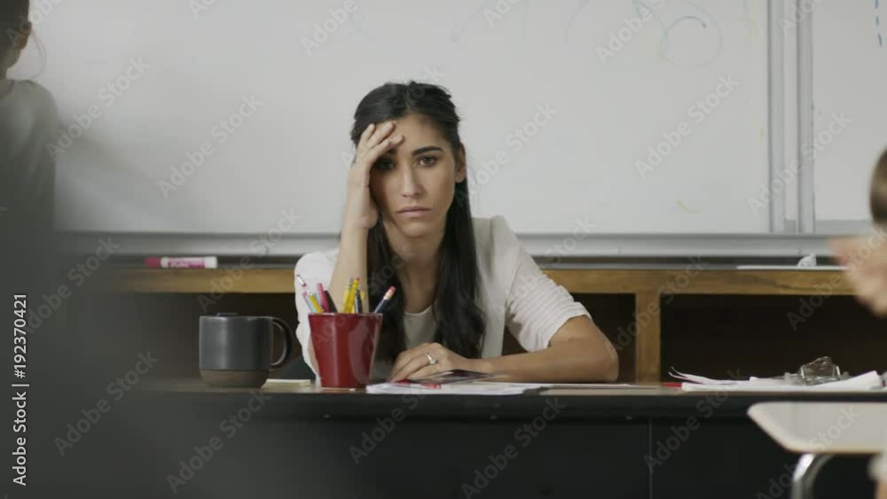 Frustrated teacher sitting at desk watching children in chaotic classroom / Provo, Utah, United States Frustrated teacher sitting at desk watching children in chaotic classroom / Provo, Utah, United States