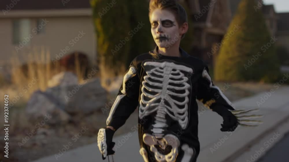 Boy wearing skeleton costume running in neighborhood on Halloween / Cedar Hills, Utah, United States Boy wearing skeleton costume running in neighborhood on Halloween / Cedar Hills, Utah, United States