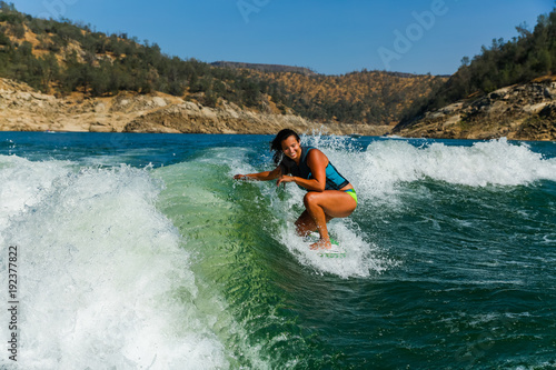 Mixed race fit young woman wakesurfing on a lake in California on a clear summer day © Jeremy Francis