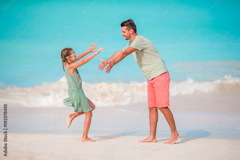 Happy father and his adorable little kid at tropical beach having fun