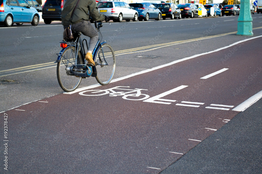 Obraz premium Cyclist on a bicycle path next to a road