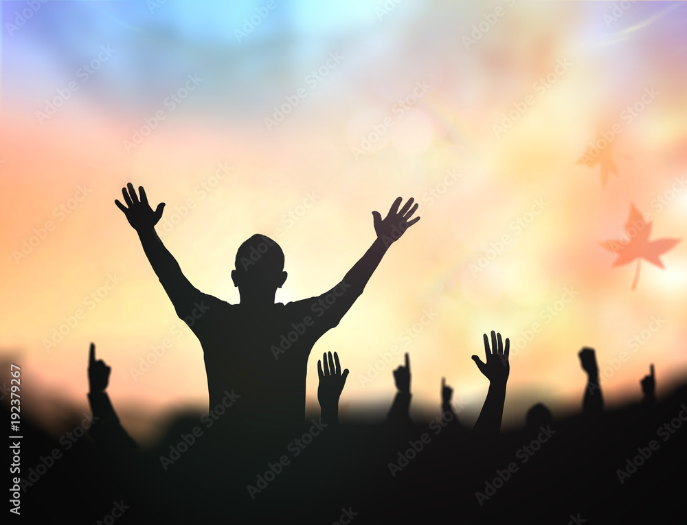 Fotografie Silhouette of a happy man raising hands with crowd during sunset with autumn lea