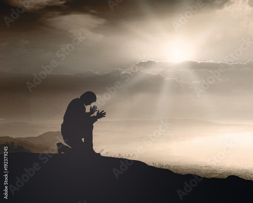 Obraz na plátně Prayer kneeling and praying to God on mountain autumn sunset background
