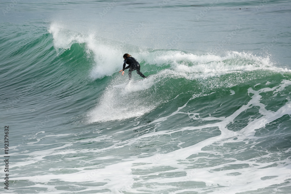 Surfer in California surfs large wave in beautiful blue water at beach