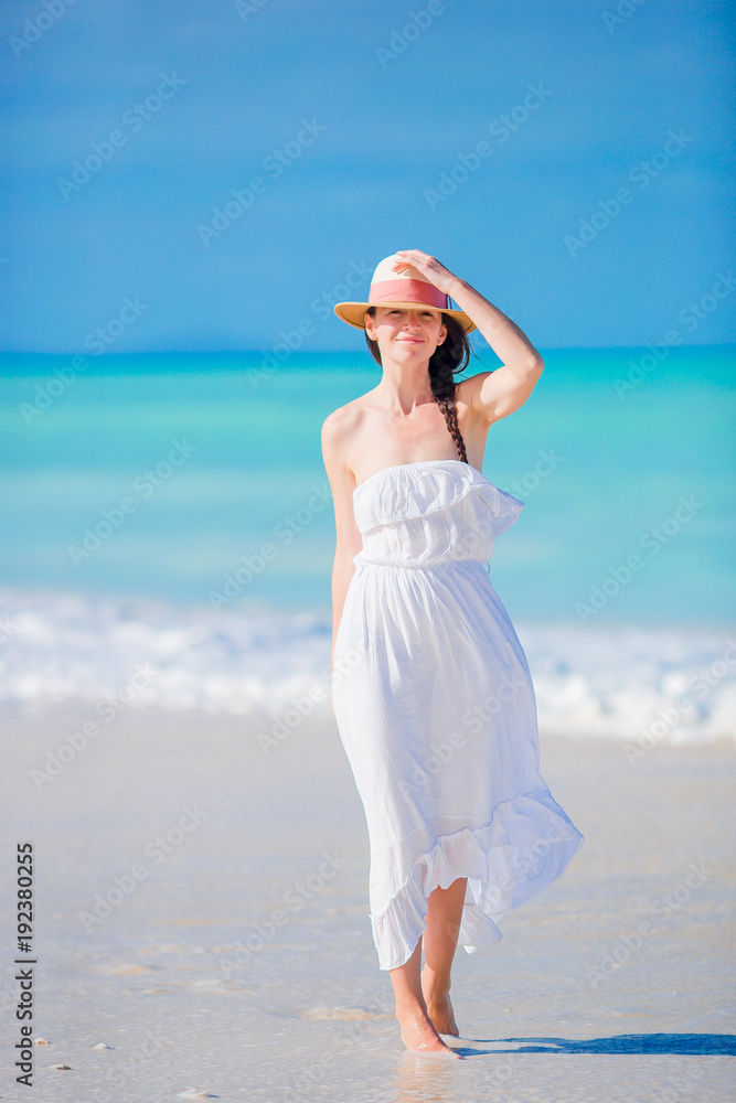 Young beautiful woman on white sand tropical beach. Caucasian girl with hat background the sea Young beautiful woman on white sand tropical beach. Caucasian girl with hat background the sea