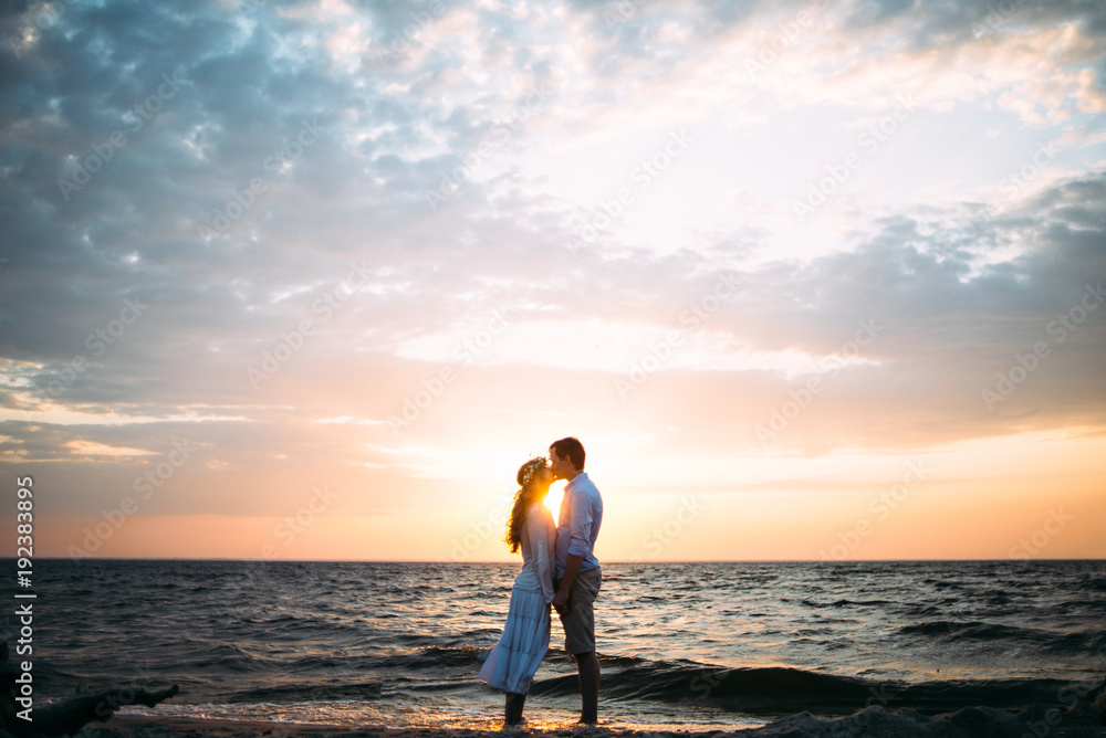 Very beautiful photo of a couple in love who stand on the seashore at sunset and kissing