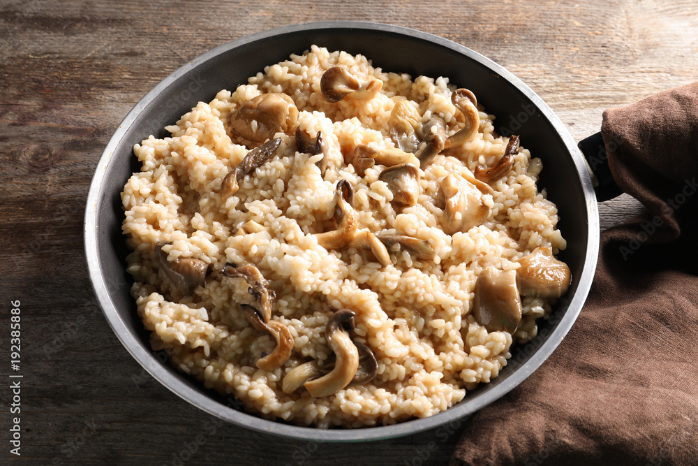 Frying pan with risotto and mushrooms on table Frying pan with risotto and mushrooms on table