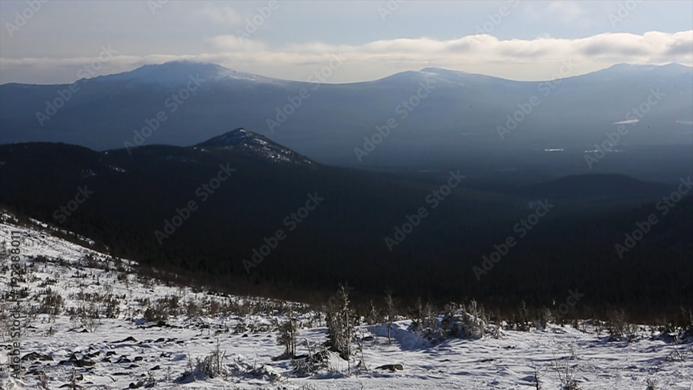 Winter mountain range scene, sun clouds and shadows over the snowy landscape. Video. Snowy mountains and sun shining. Mountain side and ridge covered in fresh powder snow