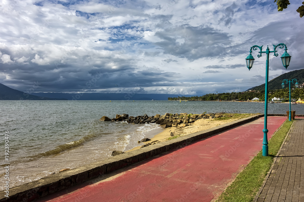 Obraz premium Bicycle lane by the sea in Ilhabela Pereque beach at sunset - Sao Paulo, Brazil
