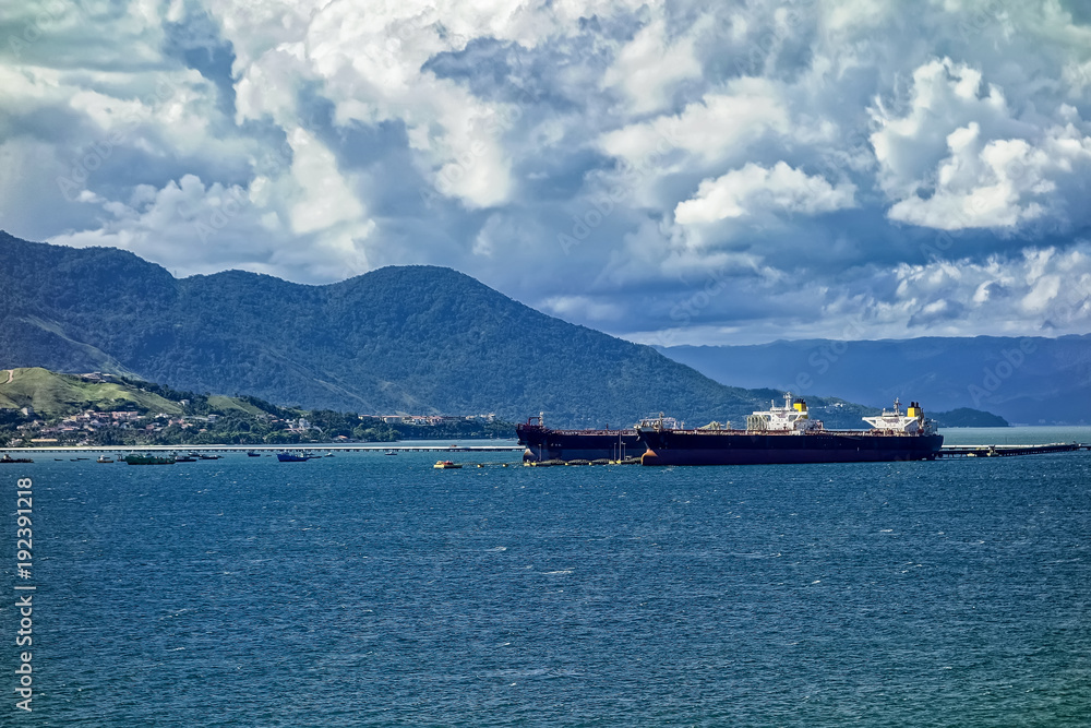 Port of Sao Sebastiao - Sao Paulo, Brazil - seen from Ilhabela with cargo ships docked on sunny day with blue sky with clouds