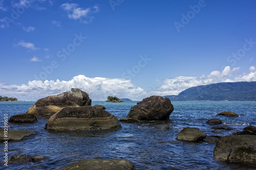View of Juliao beach in Ilhabela - Sao Paulo, Brazil - with rocks in the sea on sunny day with blue sky with clouds