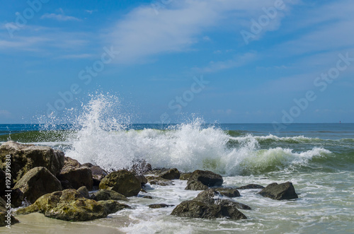 Ocean beach waves crashing onto coastal rocky shoreline. Beautiful display of natures power and beauty. Tropical travel destination location.