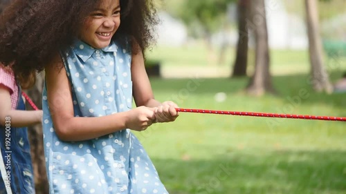 A little girl playing tug of war with her friends in a park photo