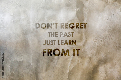 Inspirational positive quote “Don't regret the past, just learn from it.” with cement wall background.