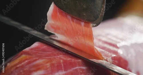 Close up macro of a chef who cuts a slice of ham, of excellent quality, with the knife according to tradition. Concept of: ham, food, Spain and Italy, catering. photo