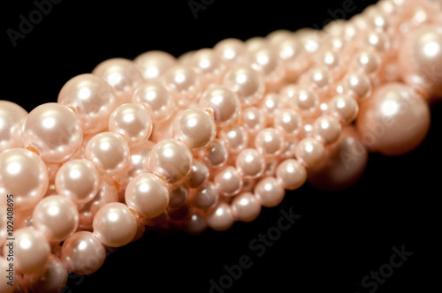 Various strands of pink pearls on a black background