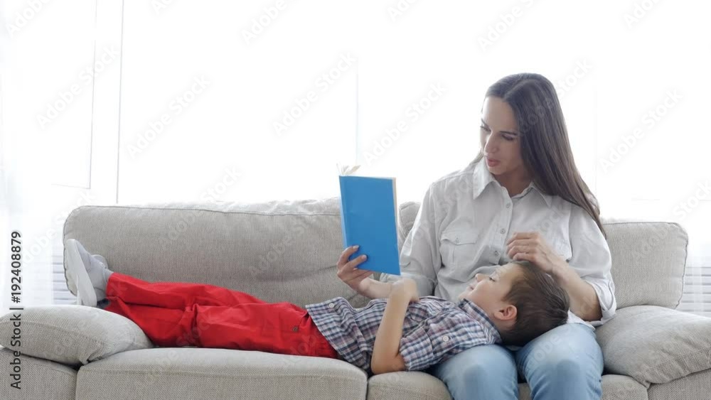 Mother and son reading book while spending time together at home Mother and son reading book while spending time together at home