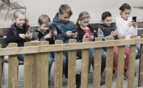 Little boys and girls sitting with smartphones