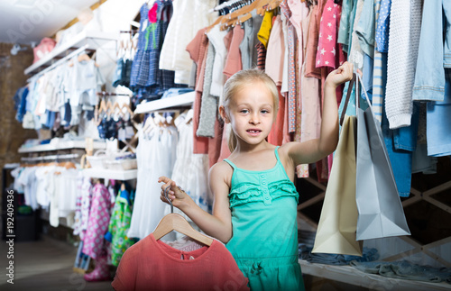 portrait of  girl standing in kids clothes store with shopping bags © JackF