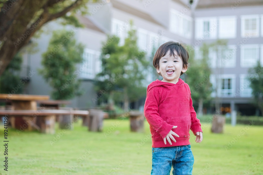 Fototapeta premium Closeup happy asian kid stand on grass floor in the garden background with fun motion
