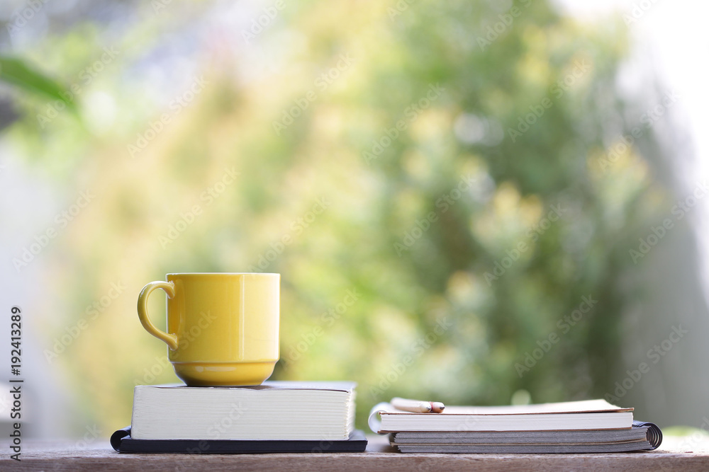 Yellow cup with books on wooden table at outdoor Yellow cup with books on wooden table at outdoor