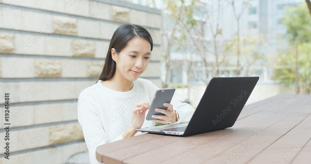 Woman using laptop computer and cellphone at outdoor coffee shop Woman using laptop computer and cellphone at outdoor coffee shop