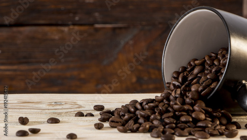 Seeds of coffee in a black cup on a wooden background photo