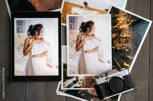 Printed wedding photos with the bride, a vintage black camera and a black tablet with a picture of bride