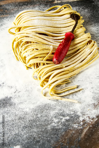 Homemade italian tagliatelle with flour. Dark background.