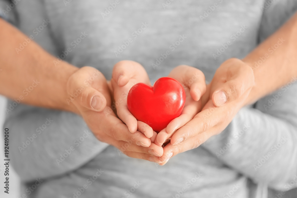 Man and woman holding small red heart in their hands Man and woman holding small red heart in their hands