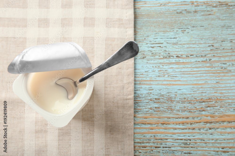 Plastic cup with yogurt on wooden background Plastic cup with yogurt on wooden background