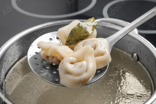 Cooked dumplings on skimmer over saucepan photo